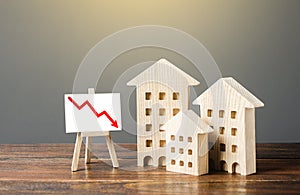 Wooden houses residential buildings and an easel with a red down arrow. Fall of real estate market. Value cost decrease