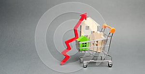 Wooden houses in a shopping cart and red arrow up. The concept of increasing the cost of housing. High demand for real estate. The