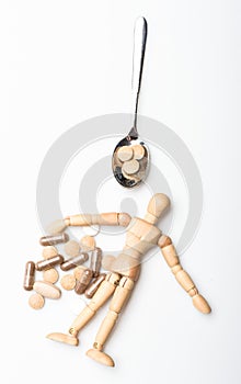Wooden human dummy near spoon full pills and tablets. Take medicine concept. Health and treatment. Health care and