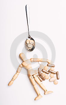 Wooden human dummy near spoon full pills and tablets. Take medicine concept. Health and treatment. Health care and