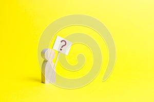 Wooden human figurine with a question mark. Minimalism. Asking a question, searching for truth and demanding truth. Curiosity
