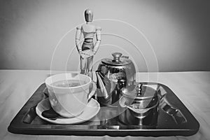 Wooden Human Manikin posing with a cup of tea on a silver tray