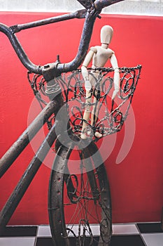 Wooden Human Manikin posing in an old rusted bicycle basket
