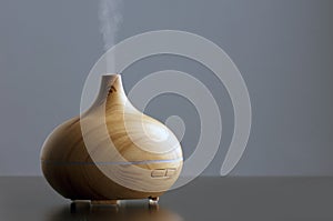 wooden humidifier for essential oils, with steam smoke, gray background