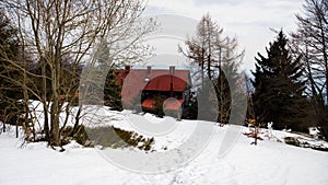 Wooden hut hidden in the forest during deep winter.