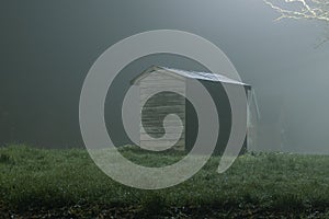 A wooden hut lit by street lights, on a moody, atmospheric, foggy winters night