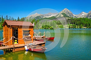 Wooden hut and red boats on mountain lake