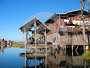 Wooden hut on stilts reflected in the waters of Inle Lake