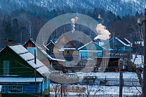 Wooden huts with smoke from chimneys in the winter season