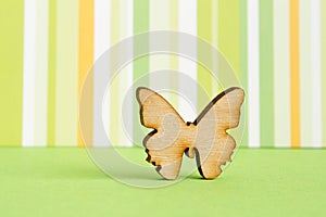 Wooden icon of butterfly on green striped background