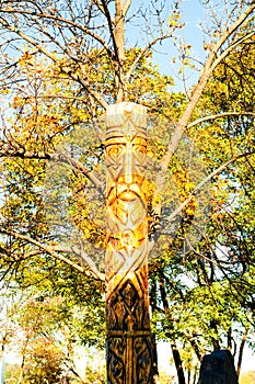 Wooden idol or pagan god against the backdrop of an autumn landscape. Close-up