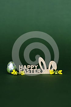 Wooden inscription Happy Easter, stylized bunny ears on a dark green background
