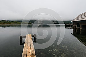 Wooden jetty in the beautiful Lake Bohinj in the Triglav National Park in Slovenia on misty morning in autumn