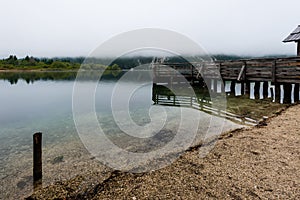 Wooden jetty in the beautiful Lake Bohinj in the Triglav National Park in Slovenia on misty morning in autumn