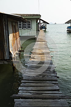 A wooden jetty crosses next to humble fishermen\'s houses, Thailand