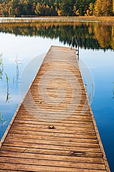 Wooden jetty by a lake with autumn colors in the forest