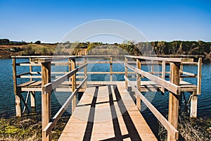 Wooden jetty at lake, river or swamp for viewers and bird watching or fishing