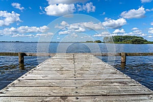 A wooden jetty made of planks sits above the water of a lake