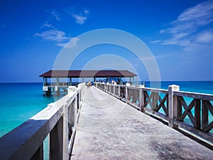 Wooden jetty in the noon under clear blue skies with people walking.