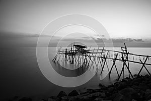 wooden Jetty with the rocky seaside during blue hour. Long Exposure Black and White