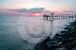 Wooden Jetty with the rocky seaside during sunset. Long exposure