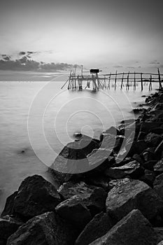 wooden Jetty with the rocky seaside during sunset. Vertical Orientation Black and White