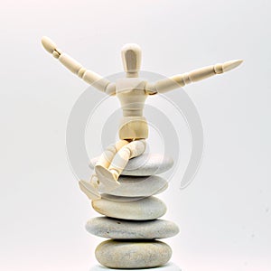 Wooden doll sitting on a pile of zen stones photo