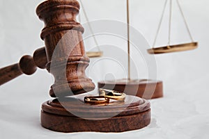 Wooden judge gavel with rings close-up on light background. Family, divorce and law concept