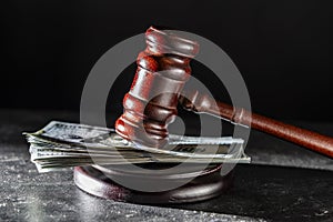 Wooden judge gavel, soundboard with dollars on the black background of a wooden table, closeup