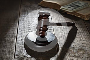 Wooden judge gavel, soundboard, old book with dollars on the background of a wooden table, closeup