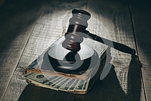 Wooden judge gavel, soundboard, old book with dollars on the background of a wooden table, closeup