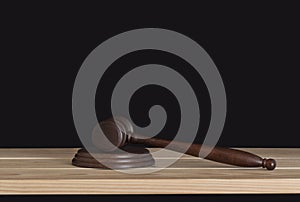 Wooden judge gavel on wooden table, black background. Wood hammer auction