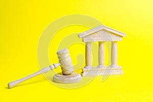 Wooden judge hammer and government building on a yellow background. Court. Concept of the state judicial system. Prohibitions