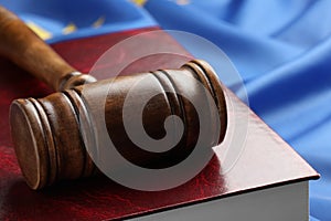 Wooden judge`s gavel and book on blue fabric, closeup