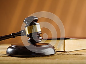 Wooden judge`s gavel and a book on a table on a beige background. Constitution, law, court, justice, rule of law. Close-up. There