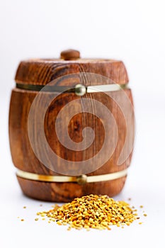 Wooden keg of honey and a scattering of pollen on a white background. Close-up