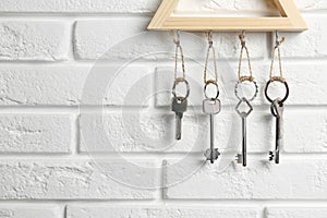 Wooden key holder on white brick wall indoors. Space for text