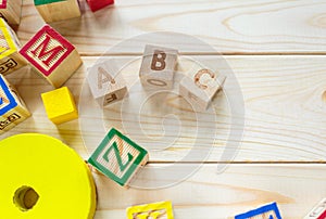 Wooden kids cubes ABC on wooden table. Educational toys blocks, pyramid, pencils, numbers. Toys for kindergarten, preschool