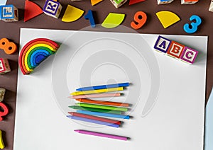 Wooden kids toys on colourful paper. Educational toys, blocks, pyramid, pencils, numbers, rainbow. Toys for kindergarten