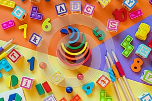 Wooden kids toys on colourful paper. Educational toys blocks, pyramid, pencils, numbers.
