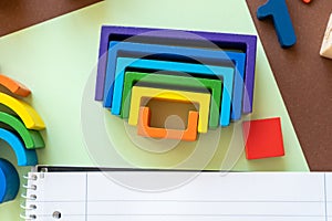 Wooden kids toys on colourful paper. Educational toys, blocks, pyramid, pencils, numbers, rainbow. Toys for kindergarten