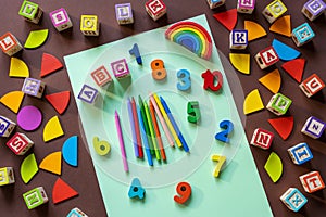 Wooden kids toys on colourful paper. Educational toys, blocks, pyramid, pencils, numbers, rainbow. Toys for kindergarten,