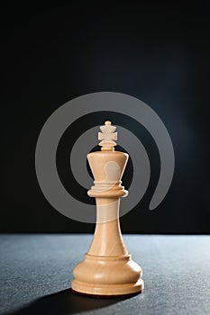Wooden king on table against dark background, space for text. Chess piece