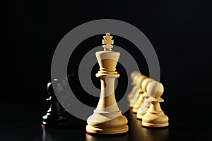 Wooden king, white and black chess pieces against dark background. Competition concept