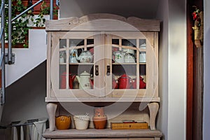 Wooden kitchen cabinet with tin pitchers and kettles