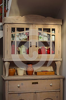 Wooden kitchen cabinet with tin pitchers and kettles