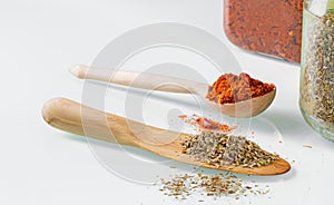 Wooden kitchen spoons filled with spices and two spice jars on a white table