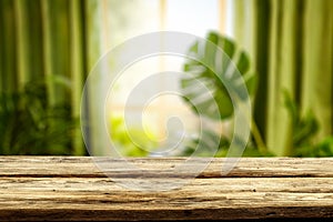 Wooden kitchen tabletop and window with blurred plants and window  background.