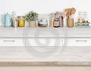 Wooden kitchen table over blurred furniture shelf with food ingredients