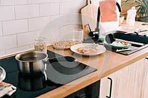 Wooden kitchen tabletop with black sink and dirty messy dish